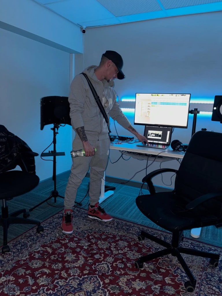 Artist working at the production desk at Warrington Music Studio with laptop, DAW on screen, and vocal mic