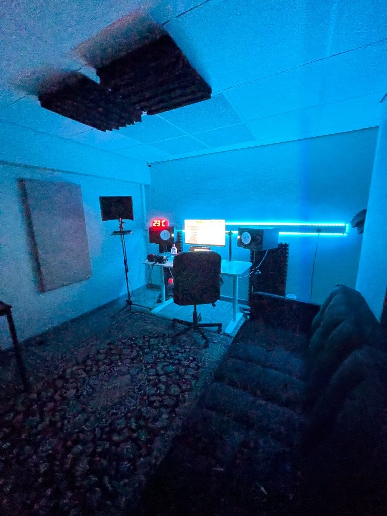 Wide view of Warrington Music Studio control room with blue LED lighting, Yamaha HS monitors, production desk, and vocal booth at Evans House.