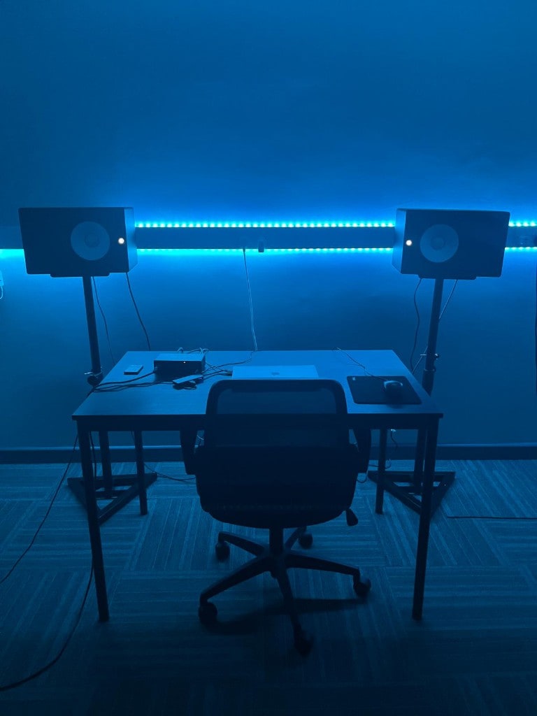 Symmetrical blue-lit Warrington Music Studio: desk, laptop, gear, and Yamaha monitors on stands.