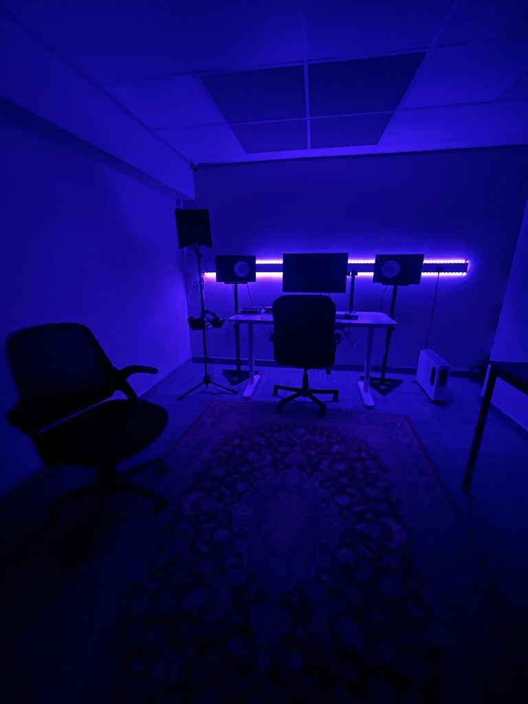 Wide angle of Warrington Music Studio with blue LED strip lighting, Yamaha monitors on stands, and production desk.