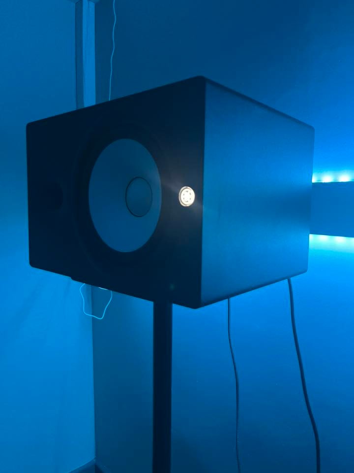 Music production desk with monitors, laptop, and vocal shield under blue LED at Warrington Music Studio.