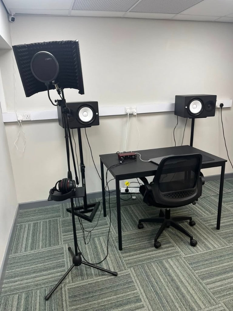 Recording workstation at Warrington Music Studio with Yamaha monitors, laptop, and vocal recording chain.
