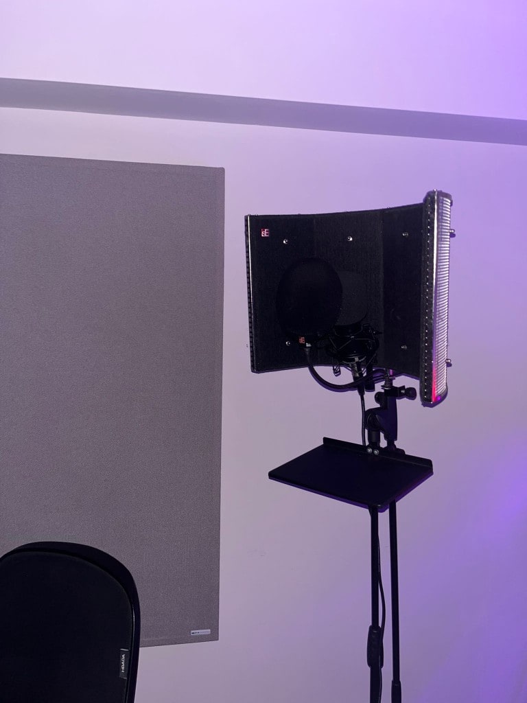 Vocal recording setup at Warrington Music Studio with sE reflection filter, pop filter, and acoustic panel in blue session lighting.