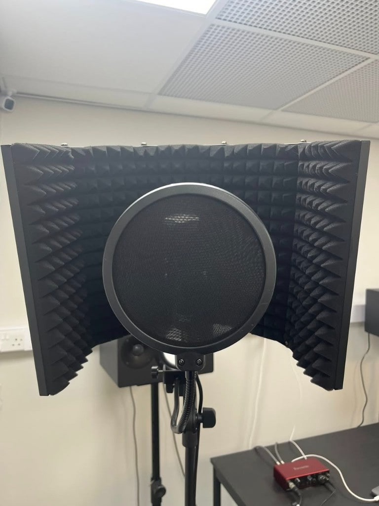 Condenser microphone with pop filter and reflection shield for vocals at Warrington Music Studio.