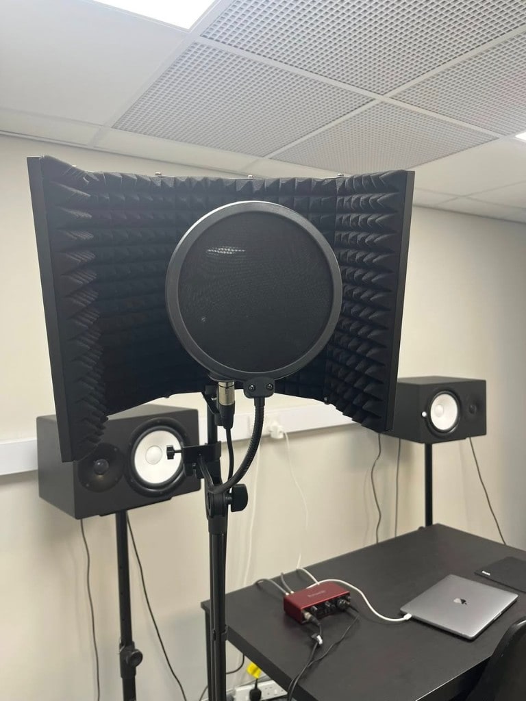 Vocal recording setup with pop filter, reflection filter, and monitors at Warrington Music Studio.