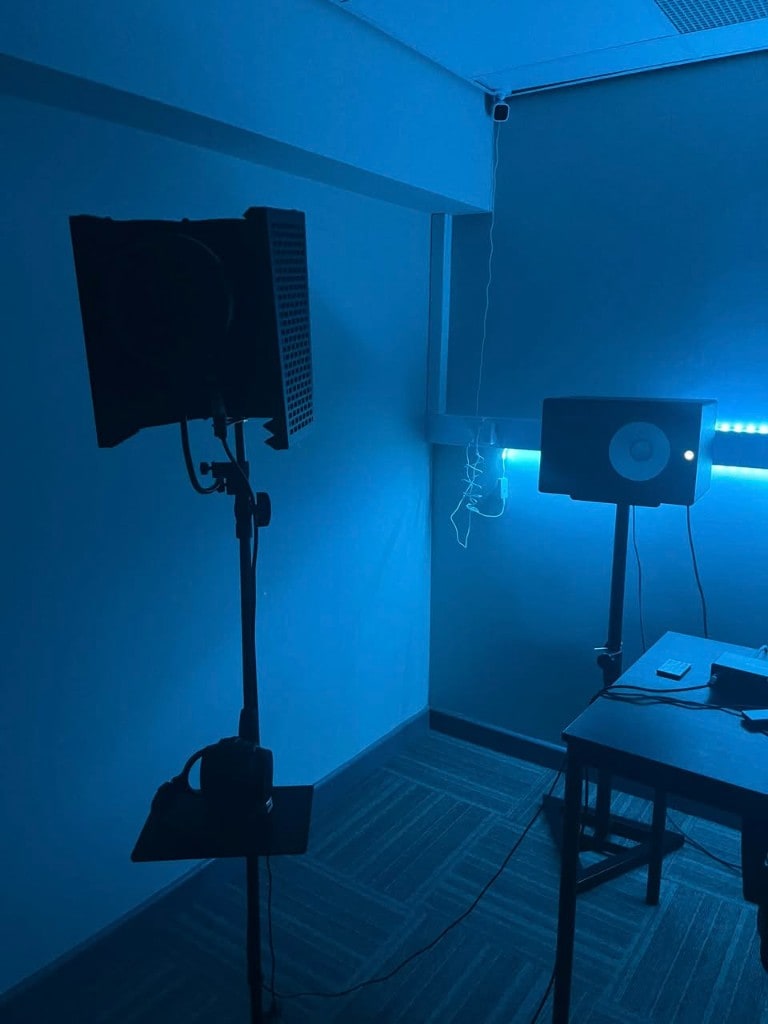 Vocal reflection filter and Yamaha monitor in blue-lit room at Warrington Music Studio.
